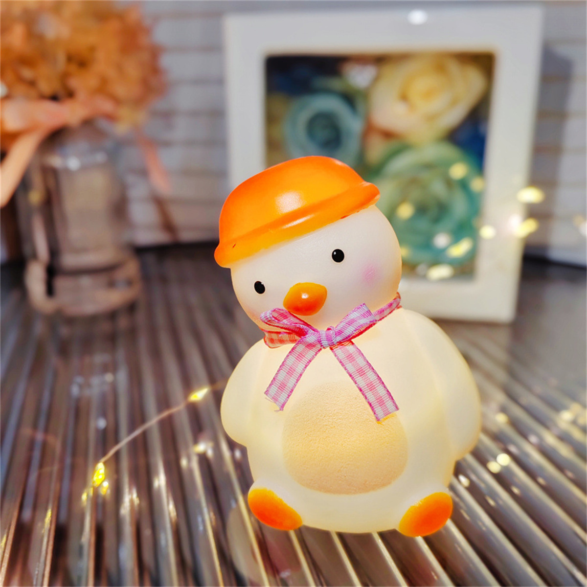 Ein pinguinförmiges Nachtlicht mit orangefarbenem Hut, rosa Schleife und beleuchtetem Körper.