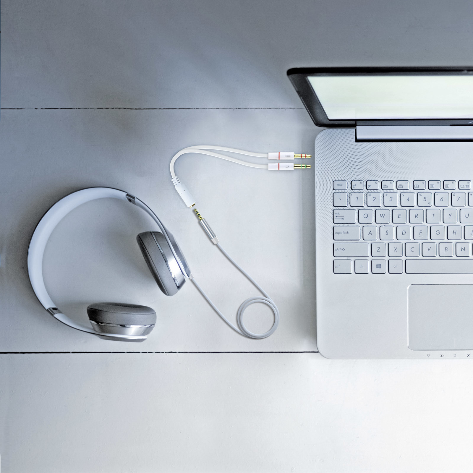 Auriculares y un portátil. Los auriculares están conectados al portátil con un cable blanco y dorado.