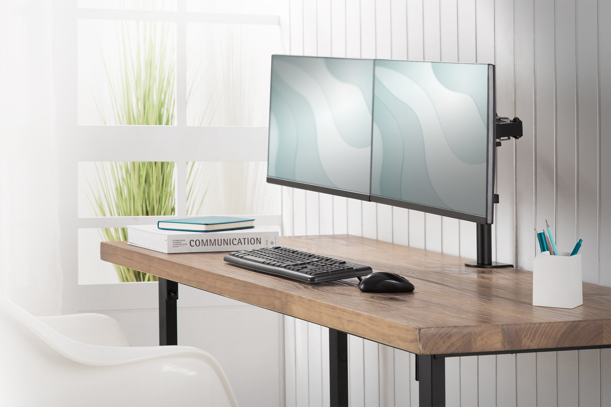 Konfiguracja biurka z dwoma monitorami, klawiaturą, myszą i rośliną.