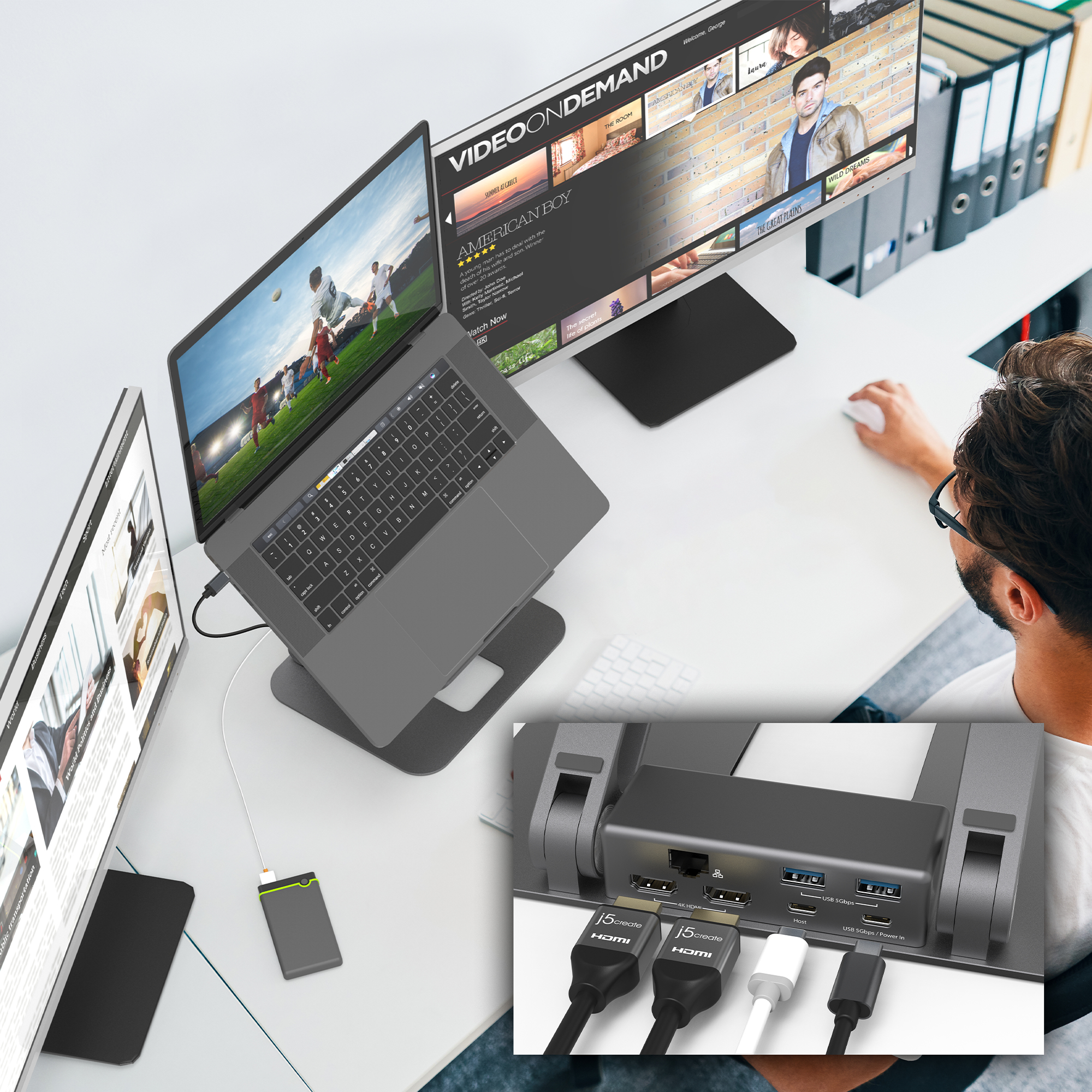 Mann arbeitet an Laptop, verbunden mit Monitor und anderen Geräten.