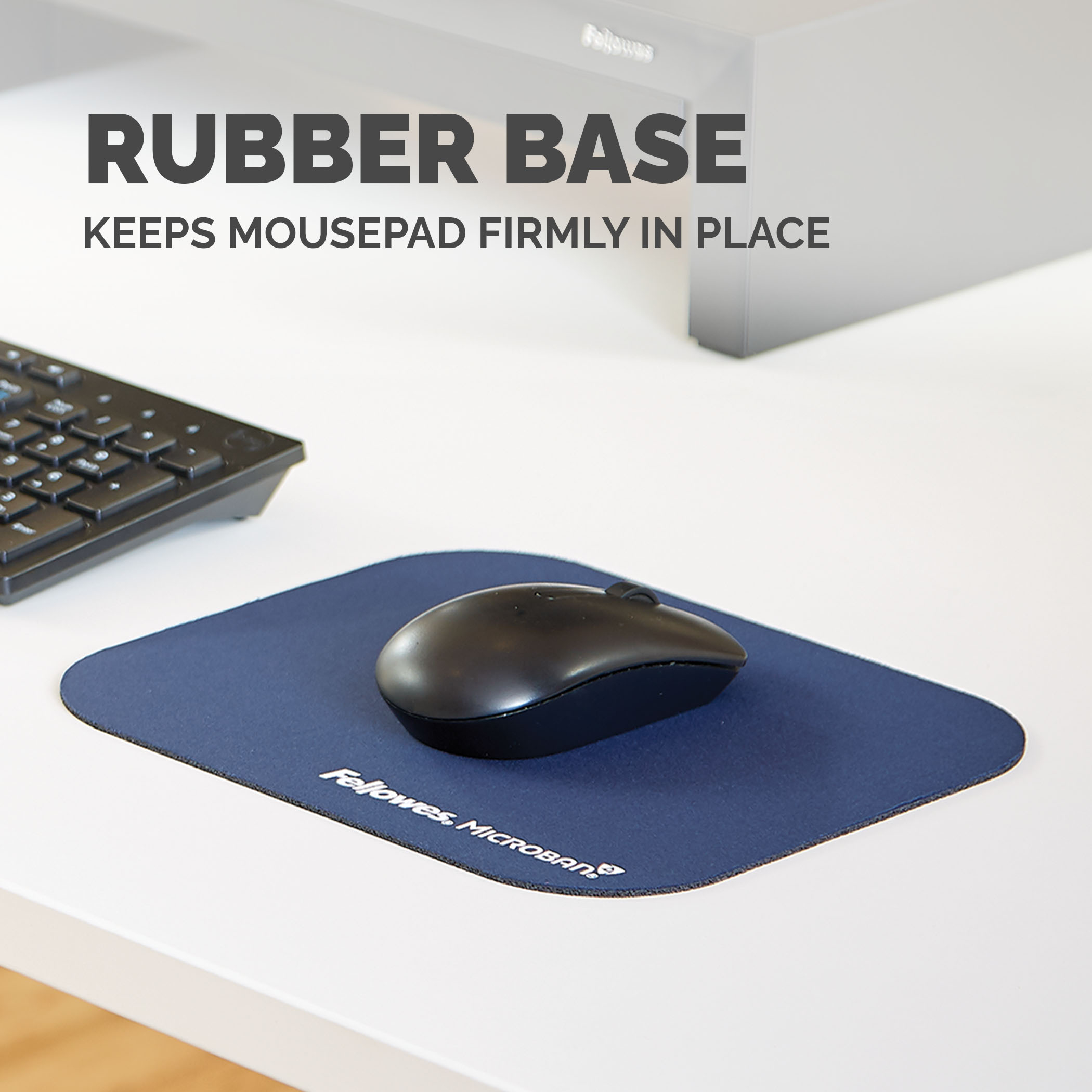 Tappetino per mouse blu con un mouse nero e una tastiera sullo sfondo su una scrivania bianca, testo sul tappetino.