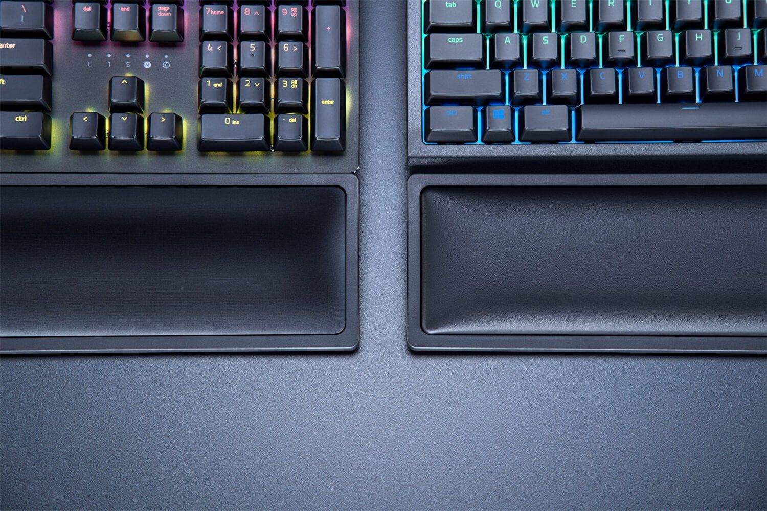 Zwei schwarze Gaming-Tastaturen mit Handgelenkauflagen. Die Tasten sind mit RGB-Lichtern beleuchtet.