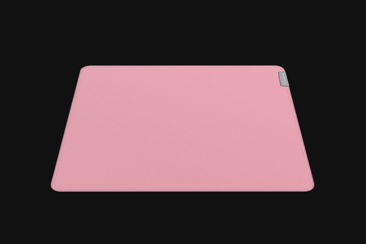 Ein rosa Mousepad auf schwarzem Hintergrund. Das Mousepad ist rechteckig und hat eine glatte Oberfläche.