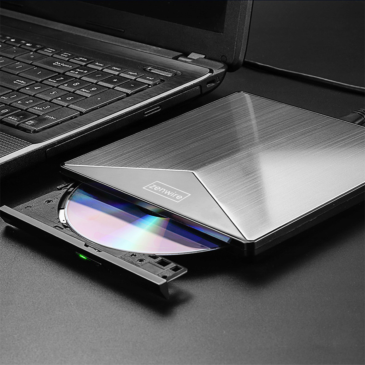 Laptop z napędem CD, otwarty z płytą CD w środku. Napęd jest srebrny i czarny.