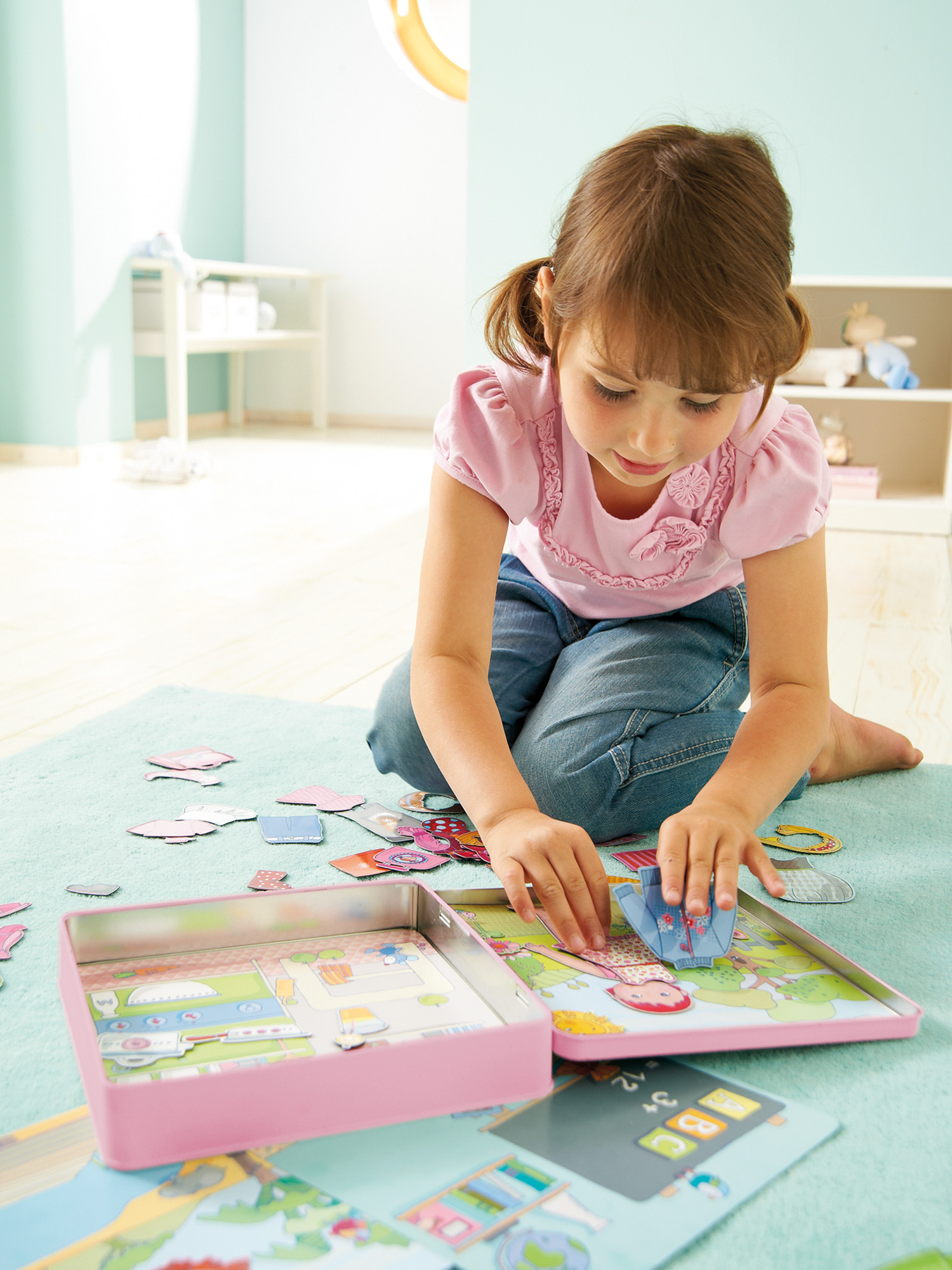Mädchen spielt mit einem rosa Puzzle auf einer blauen Matte. Eine rosa Box und Puzzleteile sind verstreut.