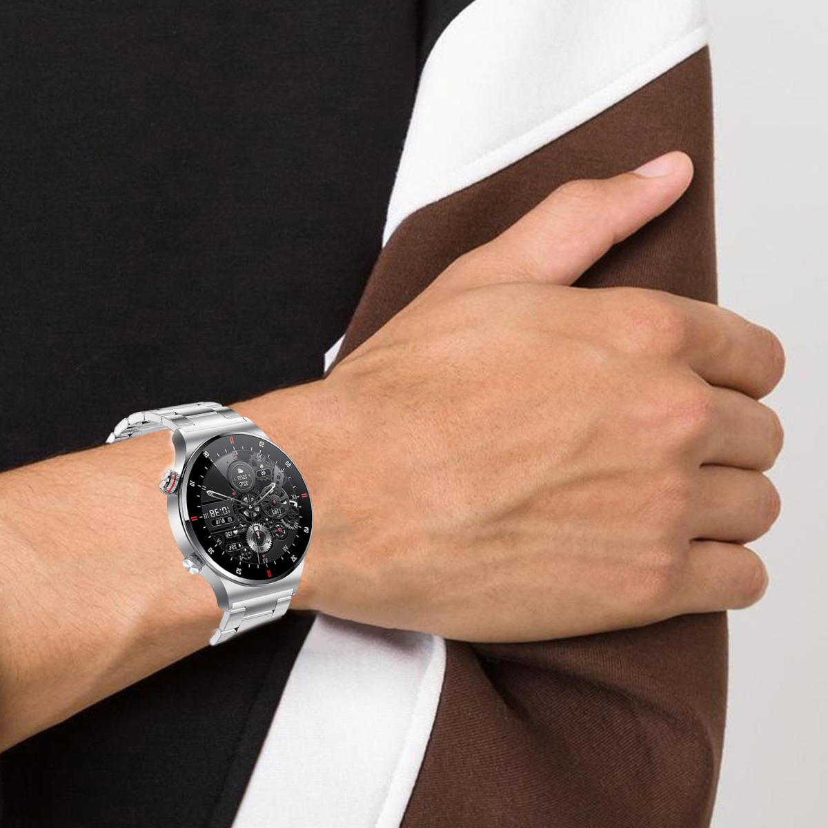Arm eines Mannes mit silberner Smartwatch am Handgelenk. Schwarz-weiß gemusterter Ärmel. Dunkler Hintergrund.
