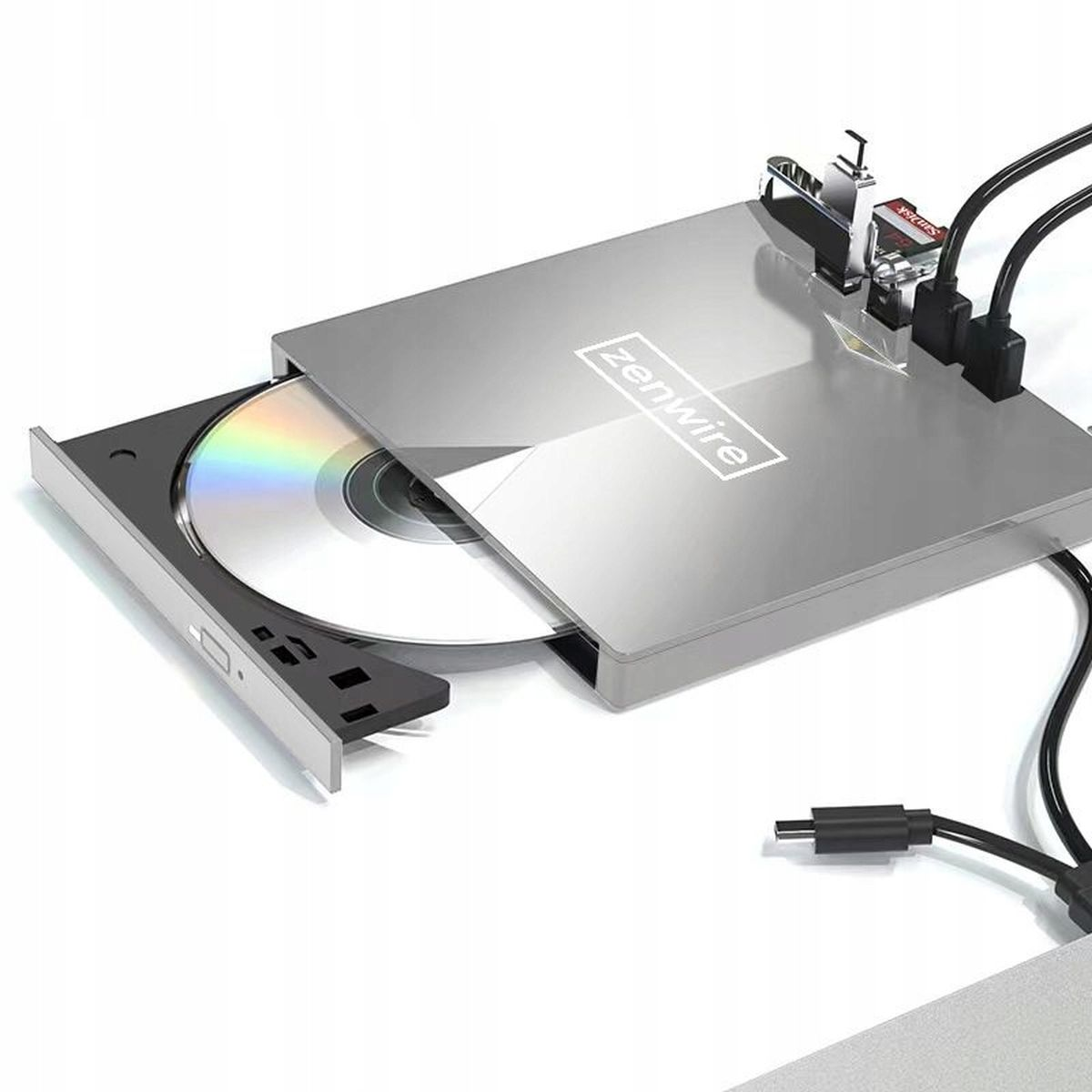 Srebrny zewnętrzny napęd CD z płytą CD w środku, podłączony do laptopa czarnym kablem.