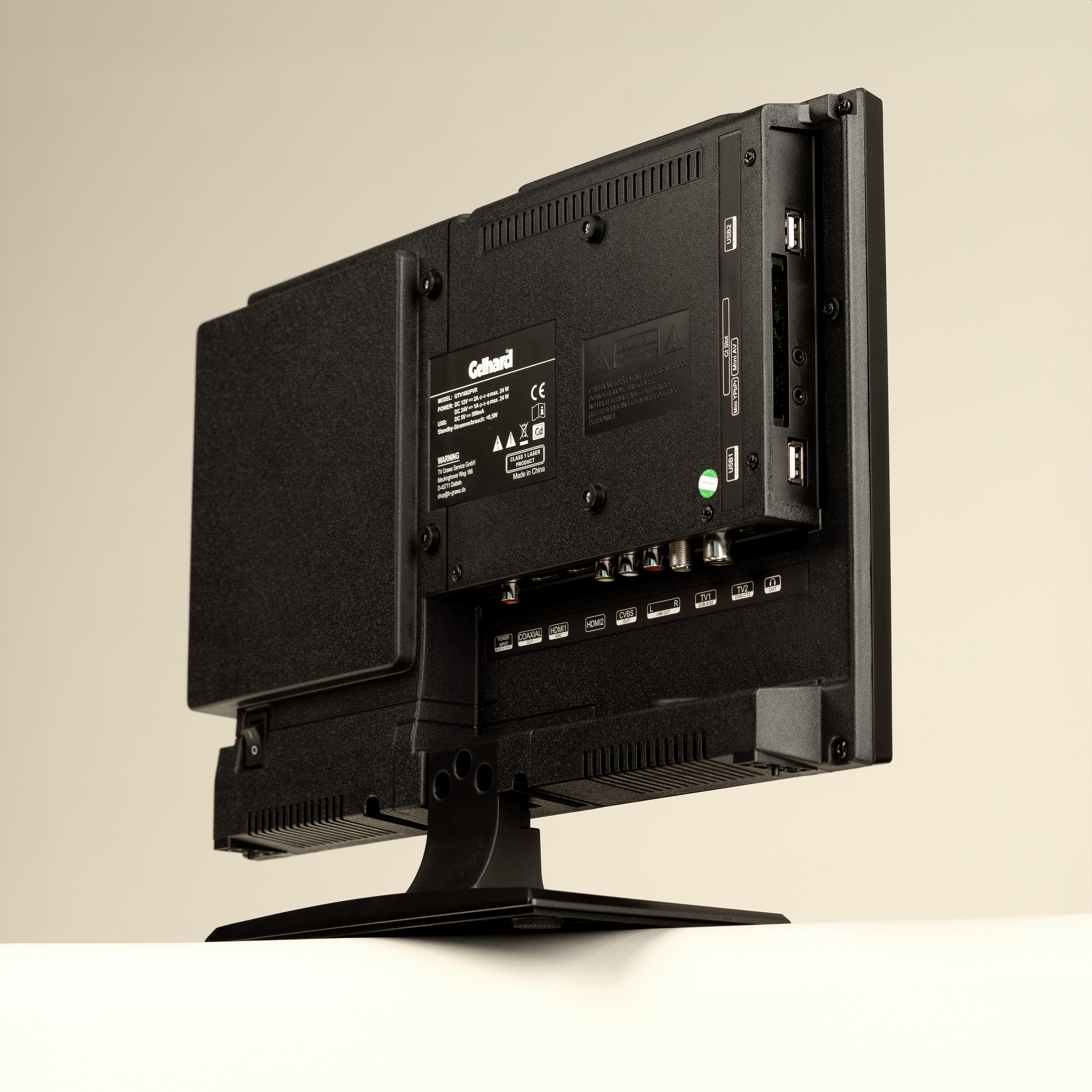 Rückansicht eines schwarzen Fernsehers, mit Anschlüssen und Verbindungen, auf weißer Oberfläche.