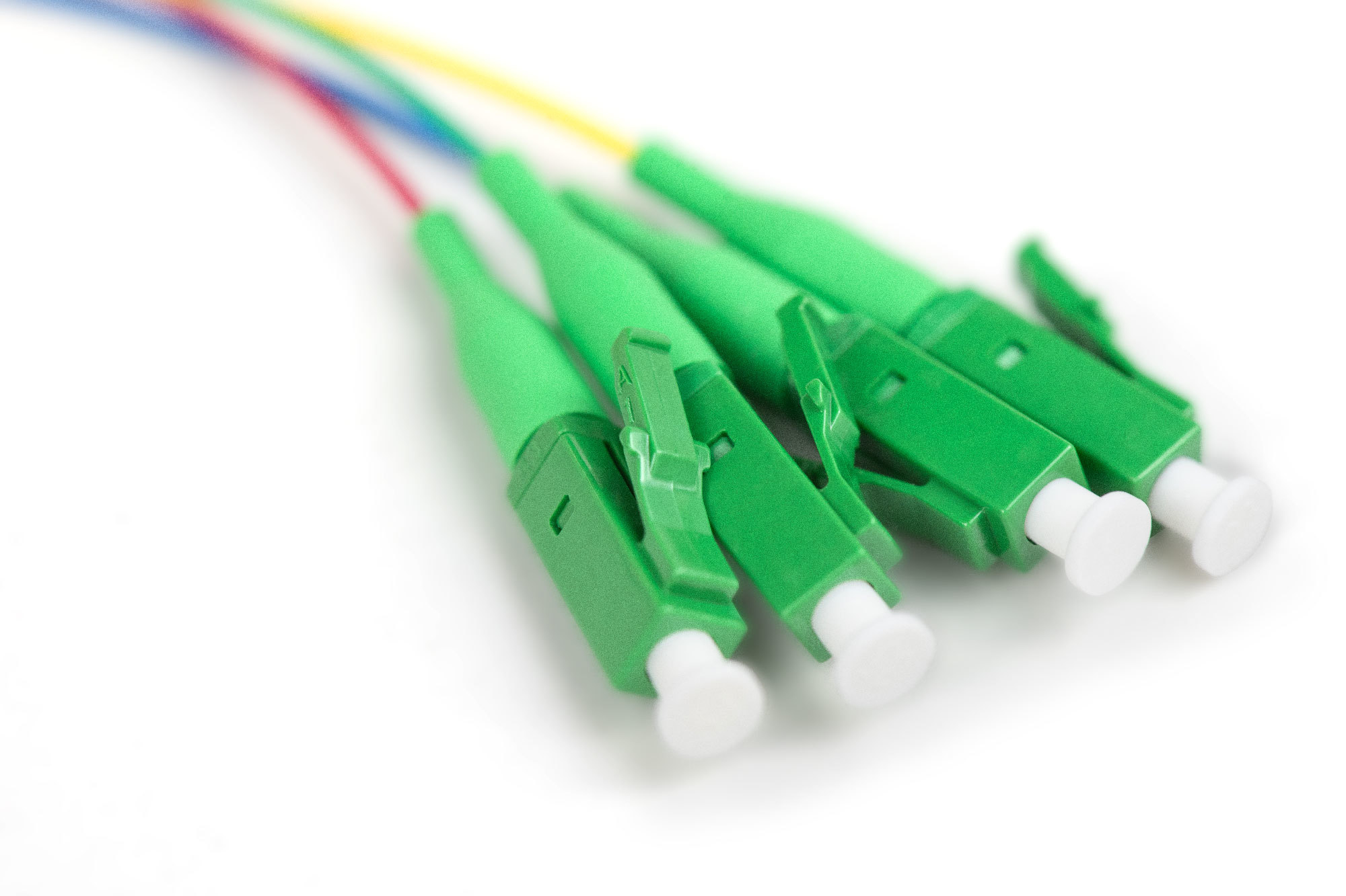 Cables de fibra óptica verdes con conectores. Están sobre fondo blanco.