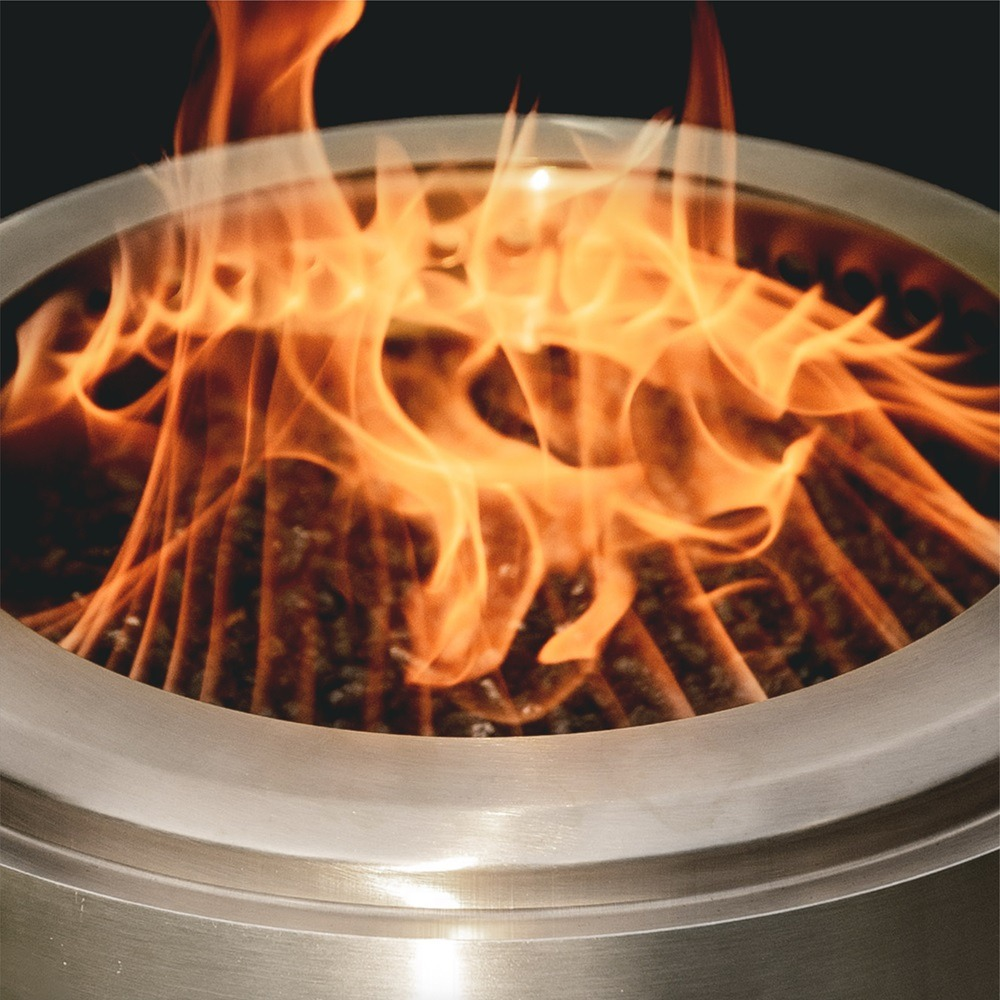Feuerstelle mit Flammen im Inneren. Silberner Metallring und dunkler Hintergrund. Nahaufnahme.