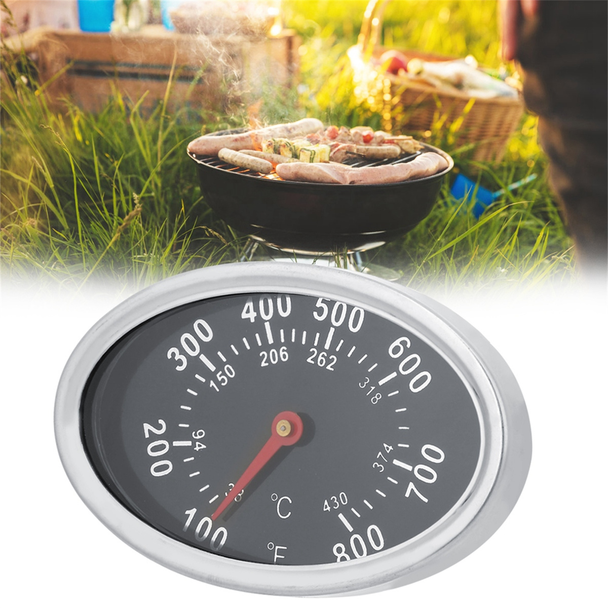 Grill mit Würstchen auf Gras, Thermometer im Vordergrund. Hintergrund: Gras, Bäume und ein Korb.