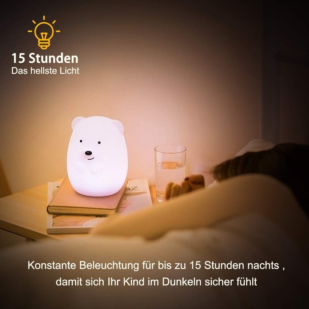 Ein weißes Bären-Nachtlicht auf einem Tisch mit Büchern und einem Glas Wasser neben einer Person.