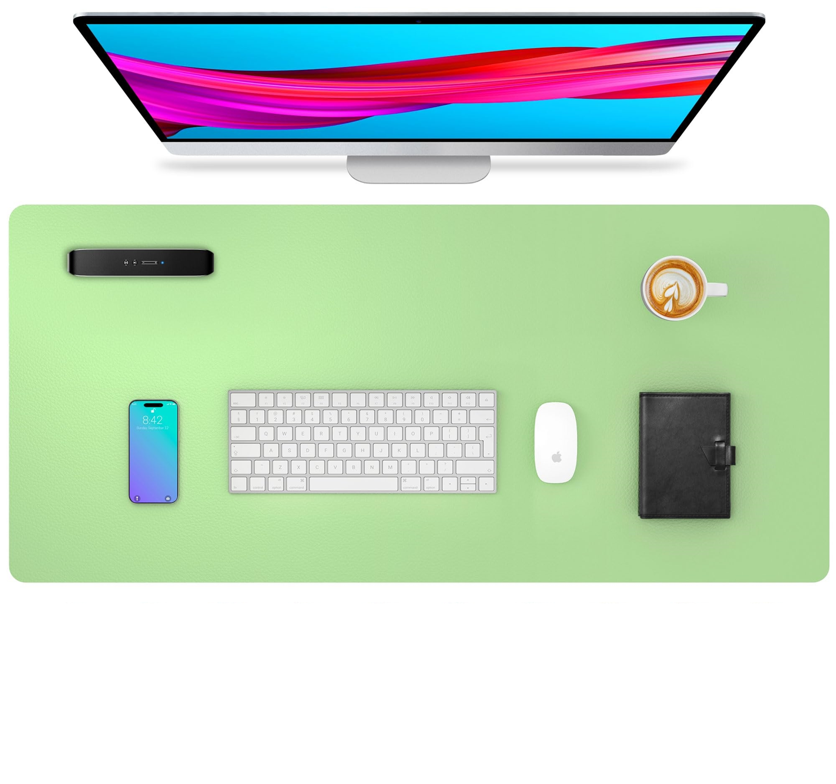 Draufsicht auf einen Schreibtisch mit Monitor, Tastatur, Telefon, Maus, Kaffeetasse und schwarzem Notizbuch.
