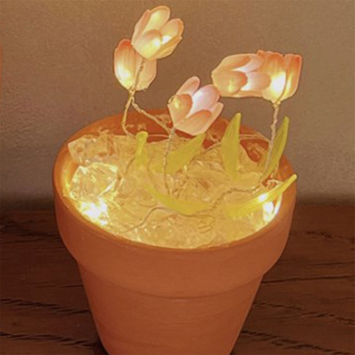 Terrakotta-Topf mit künstlichen Blumen. Die Blumen haben weiße Blütenblätter und sind von innen beleuchtet.