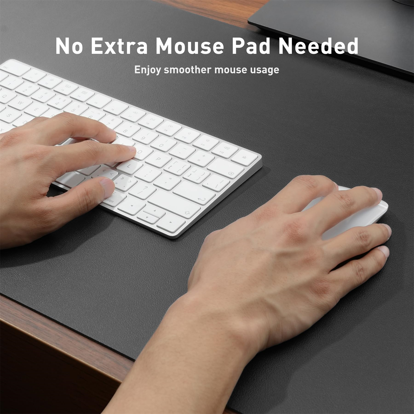 Eine Person benutzt eine weiße Tastatur und Maus auf einer schwarzen Schreibtischunterlage.
