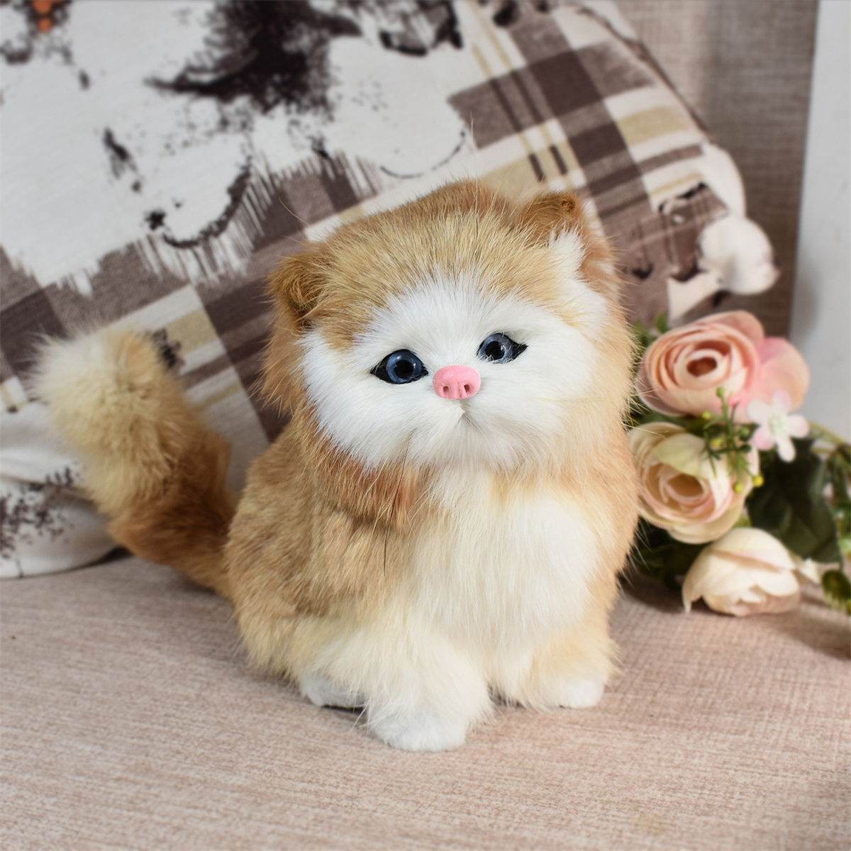 Eine flauschige Katze mit orange-weißem Fell, blauen Augen und einer rosa Nase sitzt auf einem Sofa.