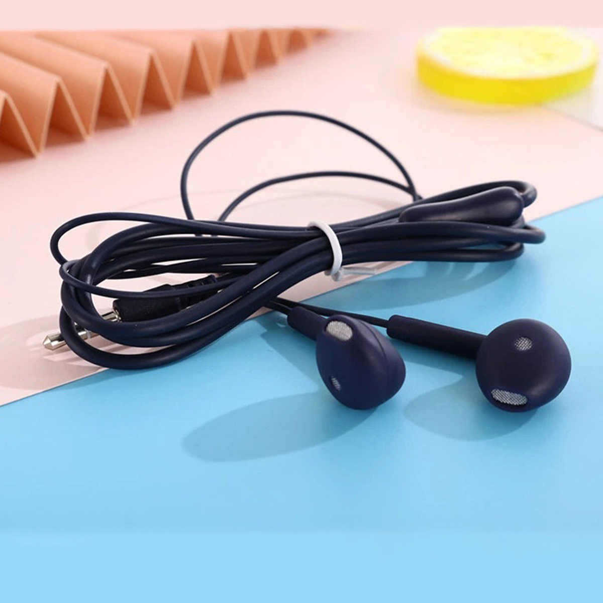 Dunkelblaue Ohrhörer mit Kabel auf blauem und rosa Hintergrund.