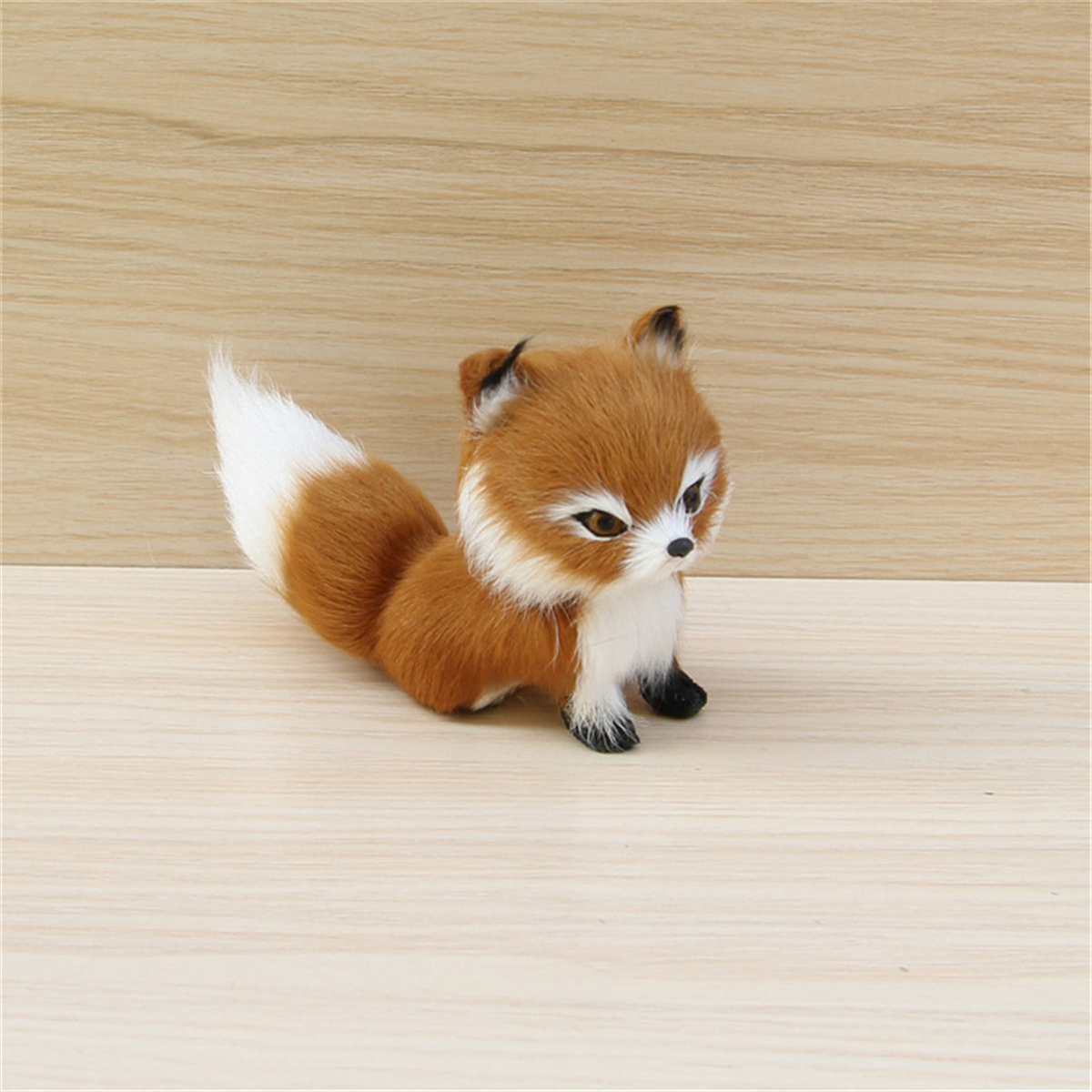 Ein Spielzeugfuchs mit braunem und weißem Fell sitzt auf Holz.