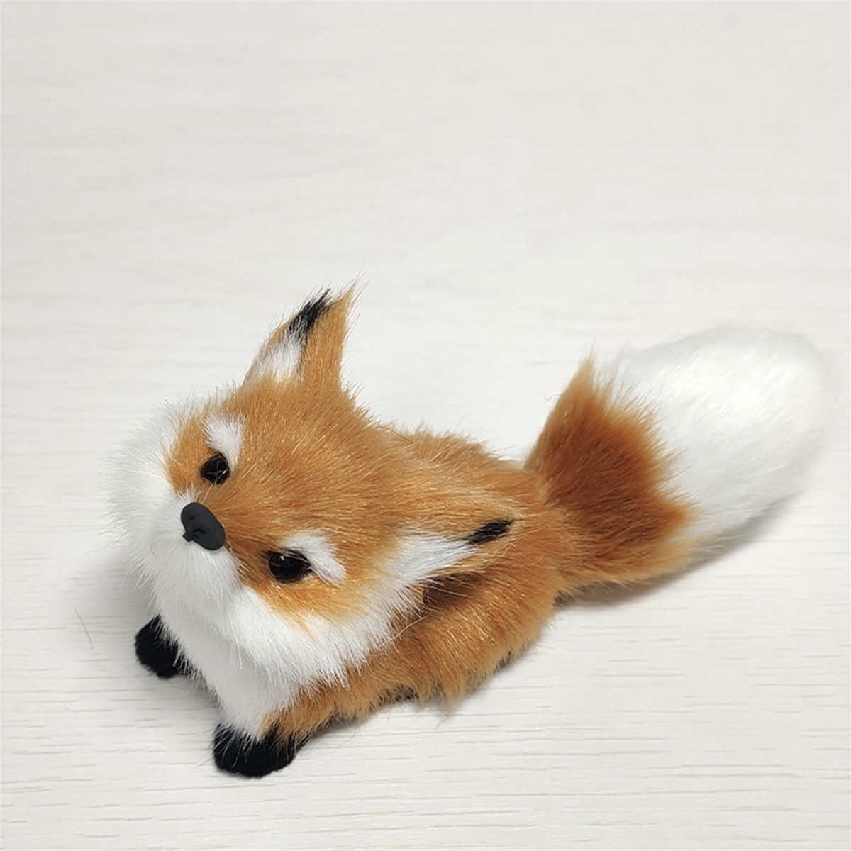 Ein kleines Spielzeug-Fuchs liegt auf einer weißen Oberfläche.