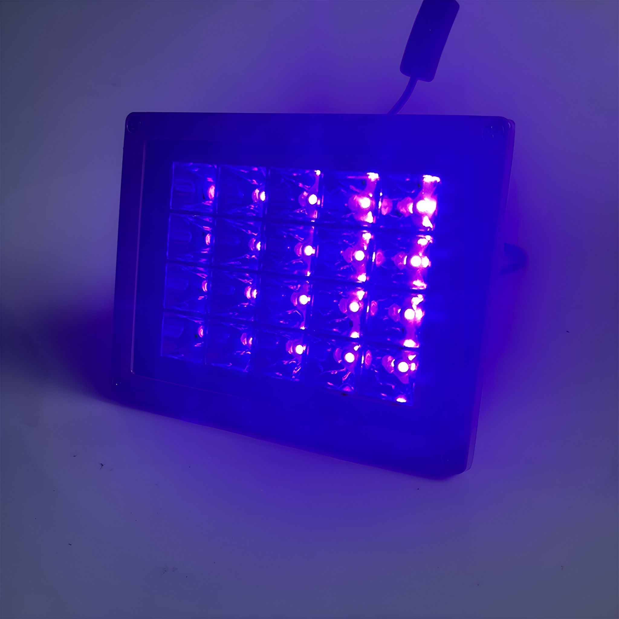 Ein schwarzes UV-Lichtpanel mit vielen kleinen violetten Lichtern. Weißer Hintergrund.
