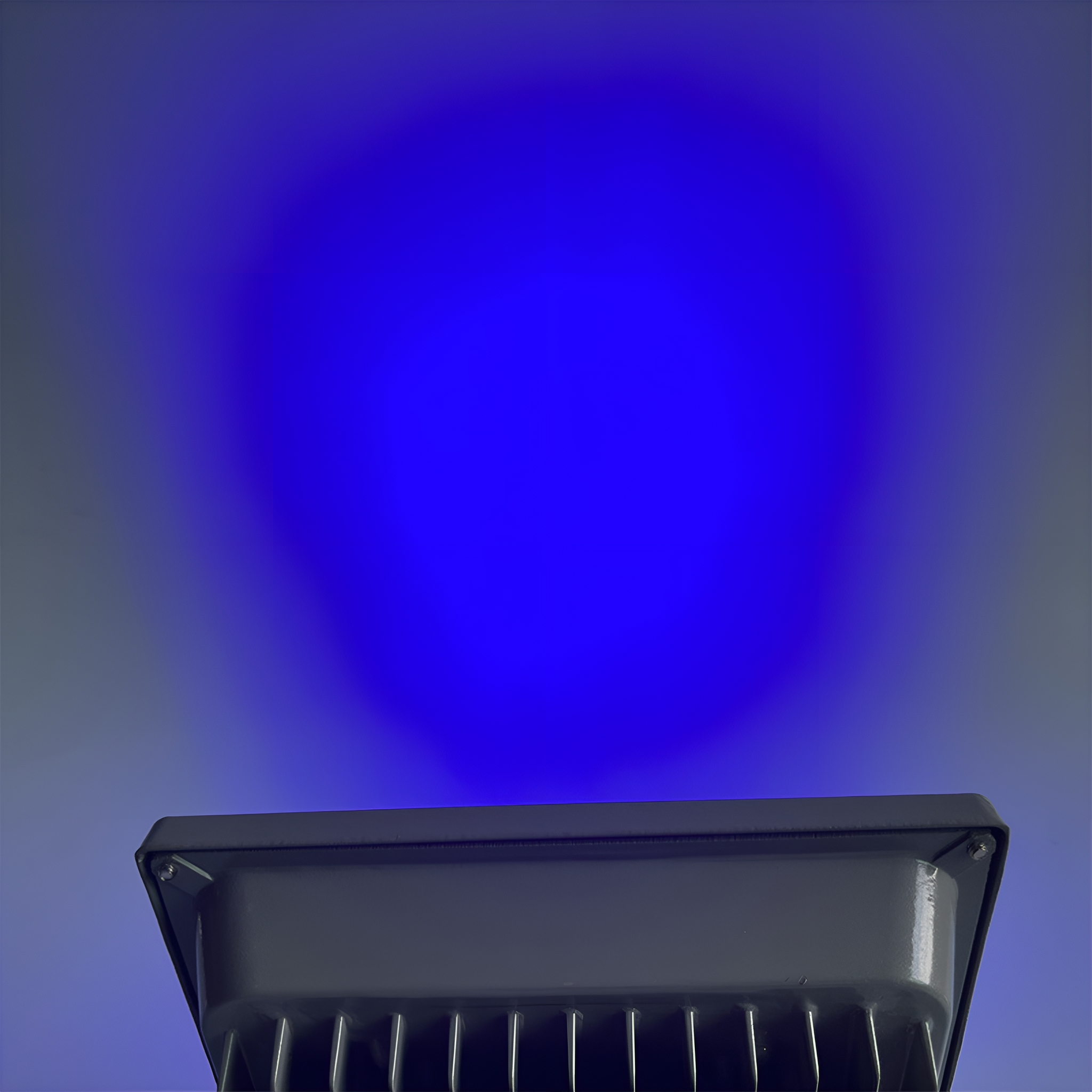 Ein schwarzer Flutlichtstrahler mit einem blauen Lichtstrahl, der von vorne heraus scheint.