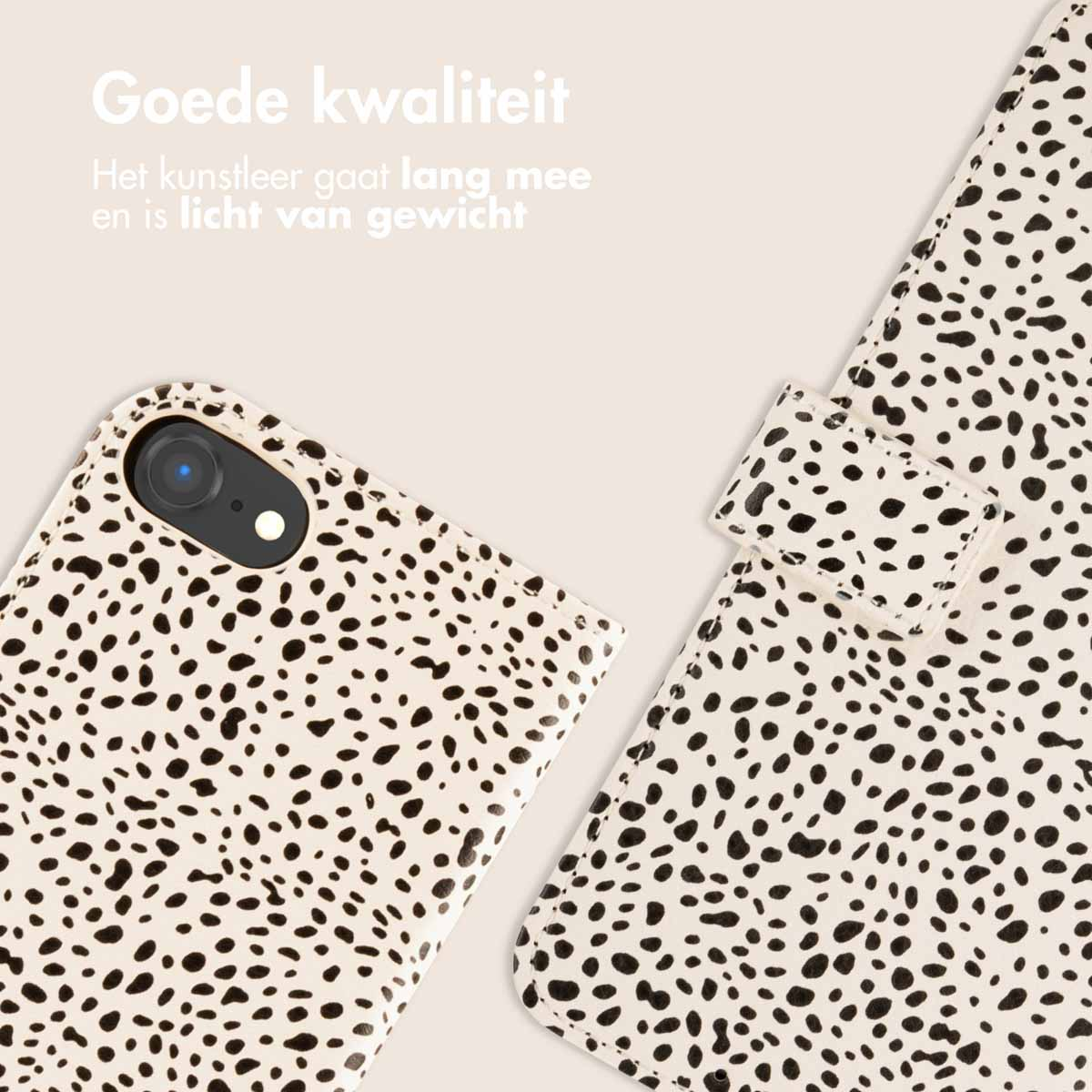 Een telefoonhoesje met een crèmekleurige achtergrond en zwarte stippen, met een bijpassende flap.
