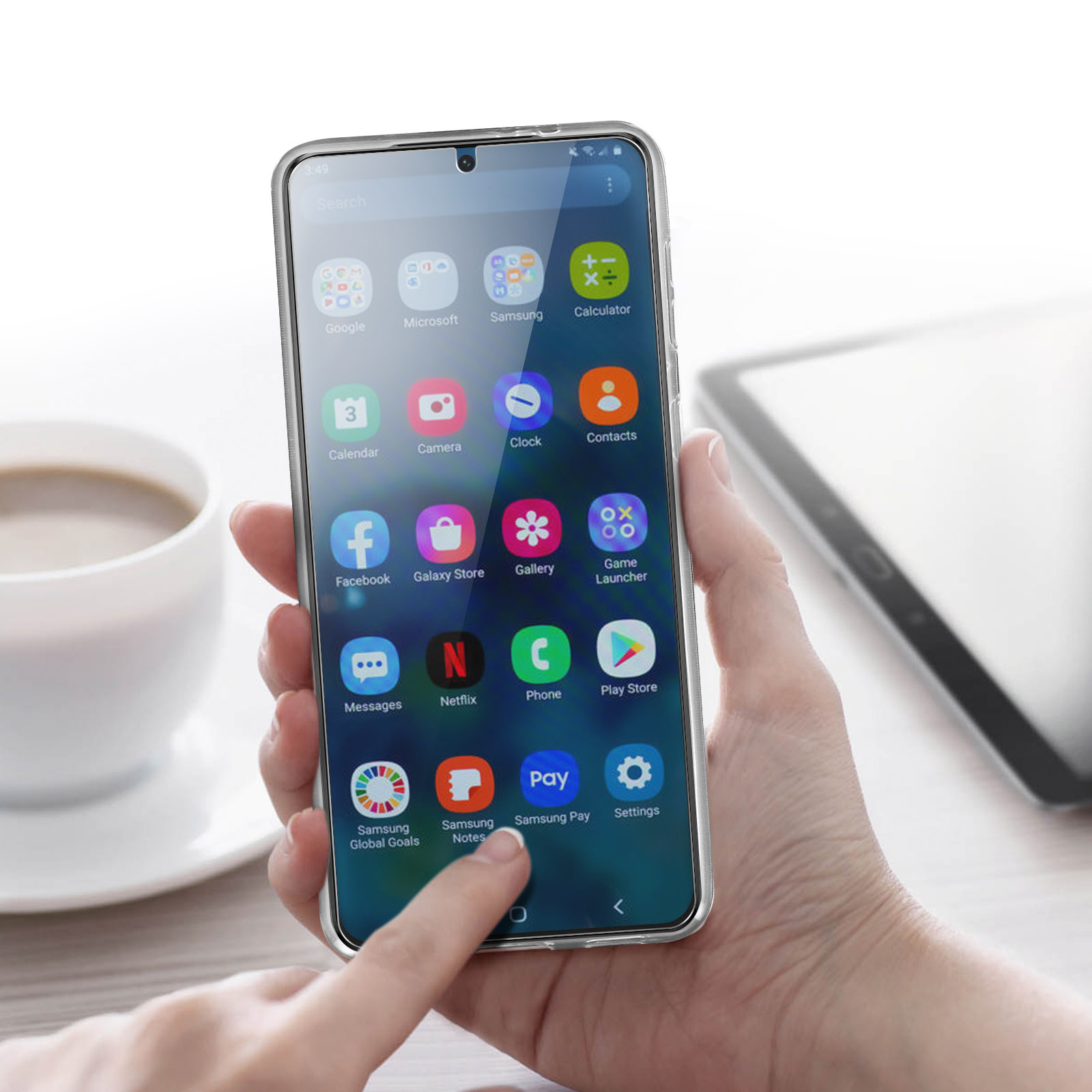 Eine Hand, die ein Telefon mit App-Symbolen auf dem Bildschirm hält. Eine Tasse und ein weiteres Telefon sind im Hintergrund.