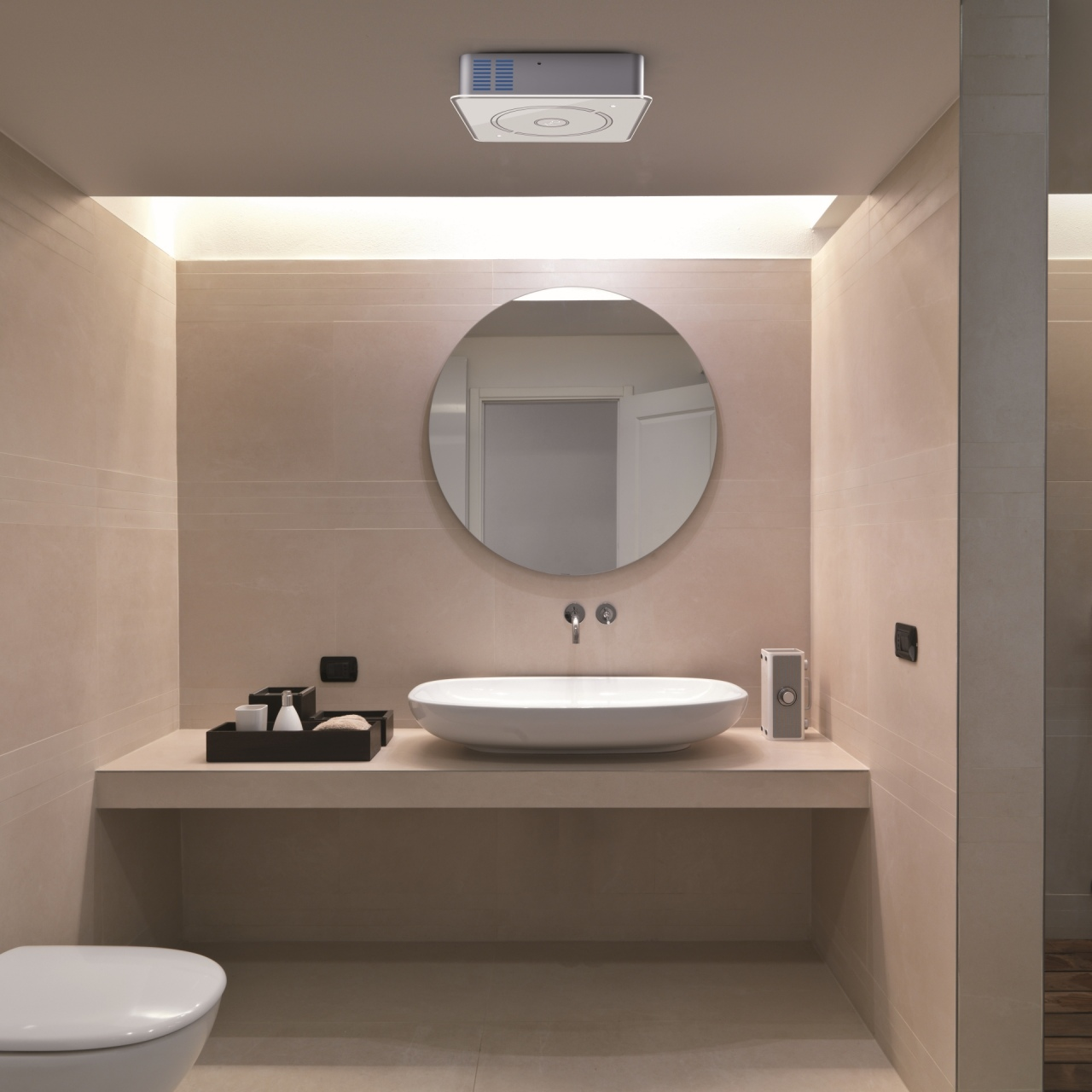 Interno bagno con specchio circolare, lavandino e toilette.