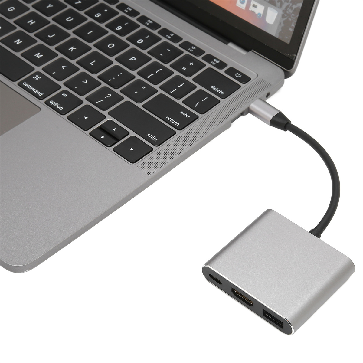 Ein silberner Laptop, der mit einem silbernen Hub mit HDMI-, USB- und USB-C-Anschluss verbunden ist.