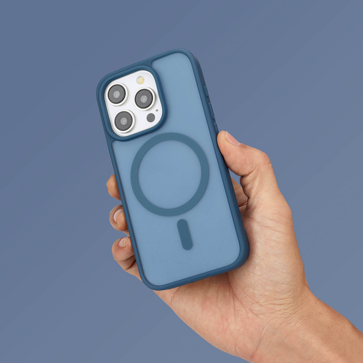 Een hand die een blauwe telefoon vasthoudt in een hoesje met een cirkel. Tekst: 'Geschikt voor MagSafe'.