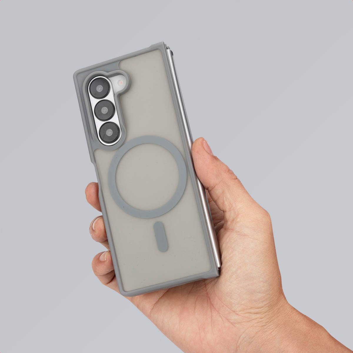 Hand die een grijze telefoonhoes met telefoon vasthoudt. Grijze achtergrond.