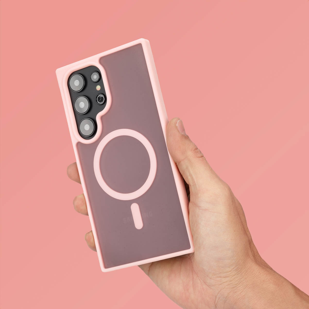 Roze telefoonhoes in de hand. Roze achtergrond. Hoes heeft een cirkel voor MagSafe. Telefoon zit erin.