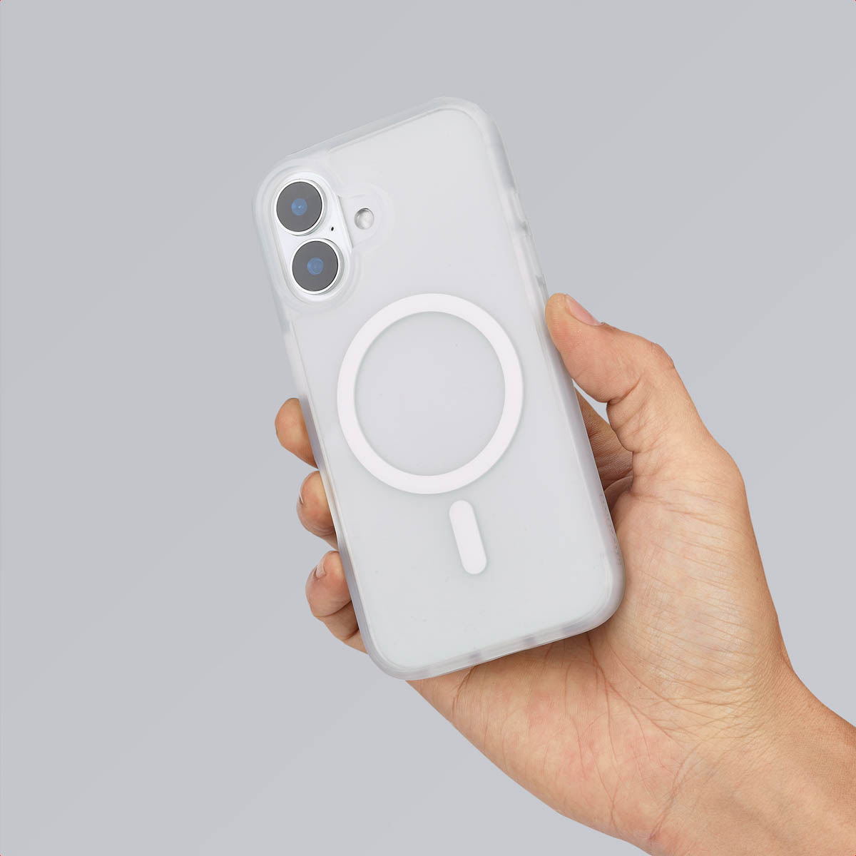 Hand houdt een telefoon met MagSafe-hoesje vast. Witte oplader, transparante hoes.
