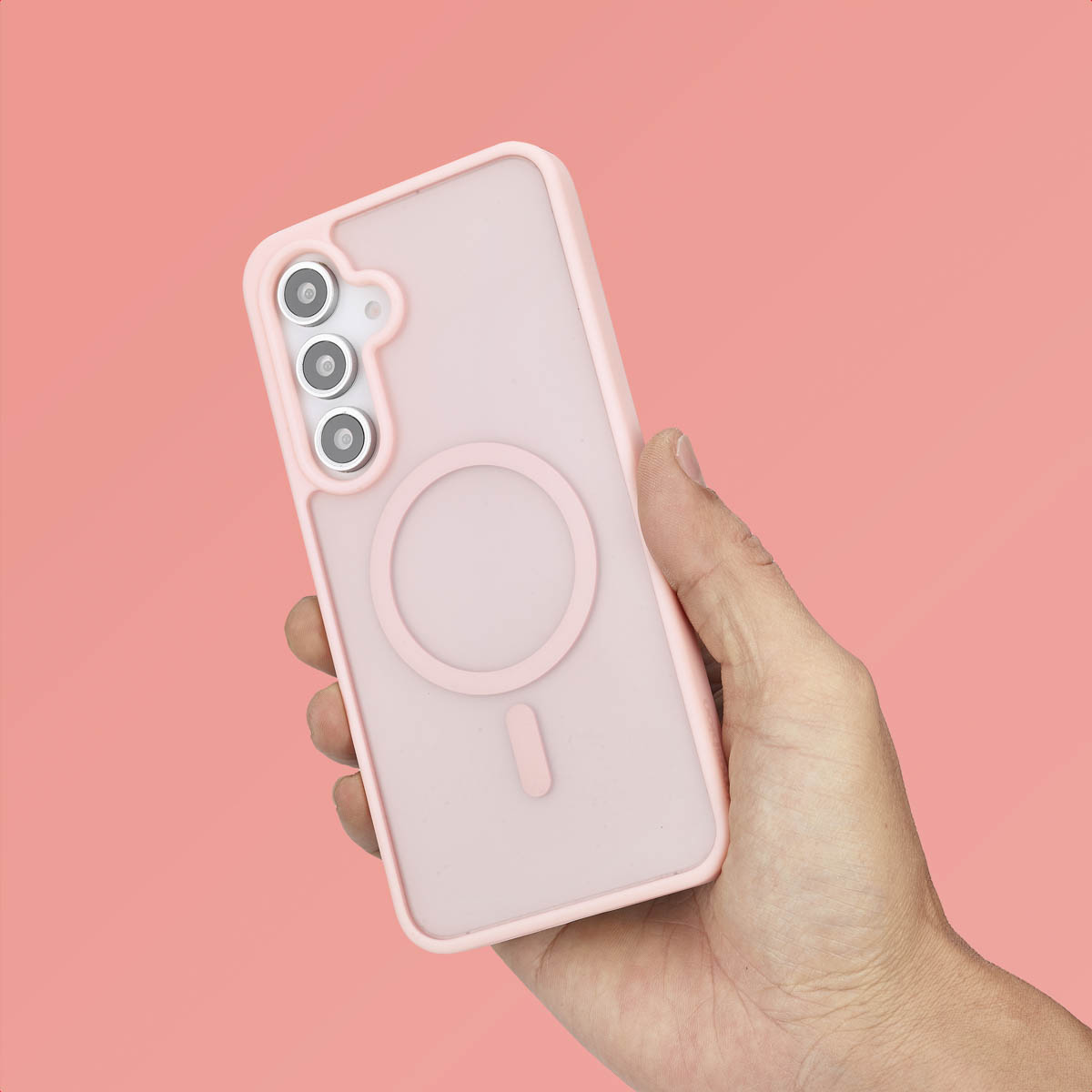 Une main tenant une coque de téléphone rose. La coque a un cercle et le téléphone est rose.