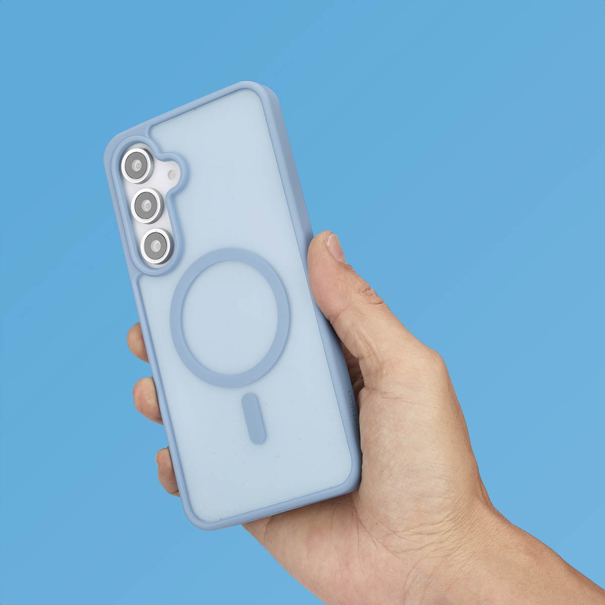 Main tenant une coque de téléphone bleu clair avec un anneau magnétique, sur fond bleu.