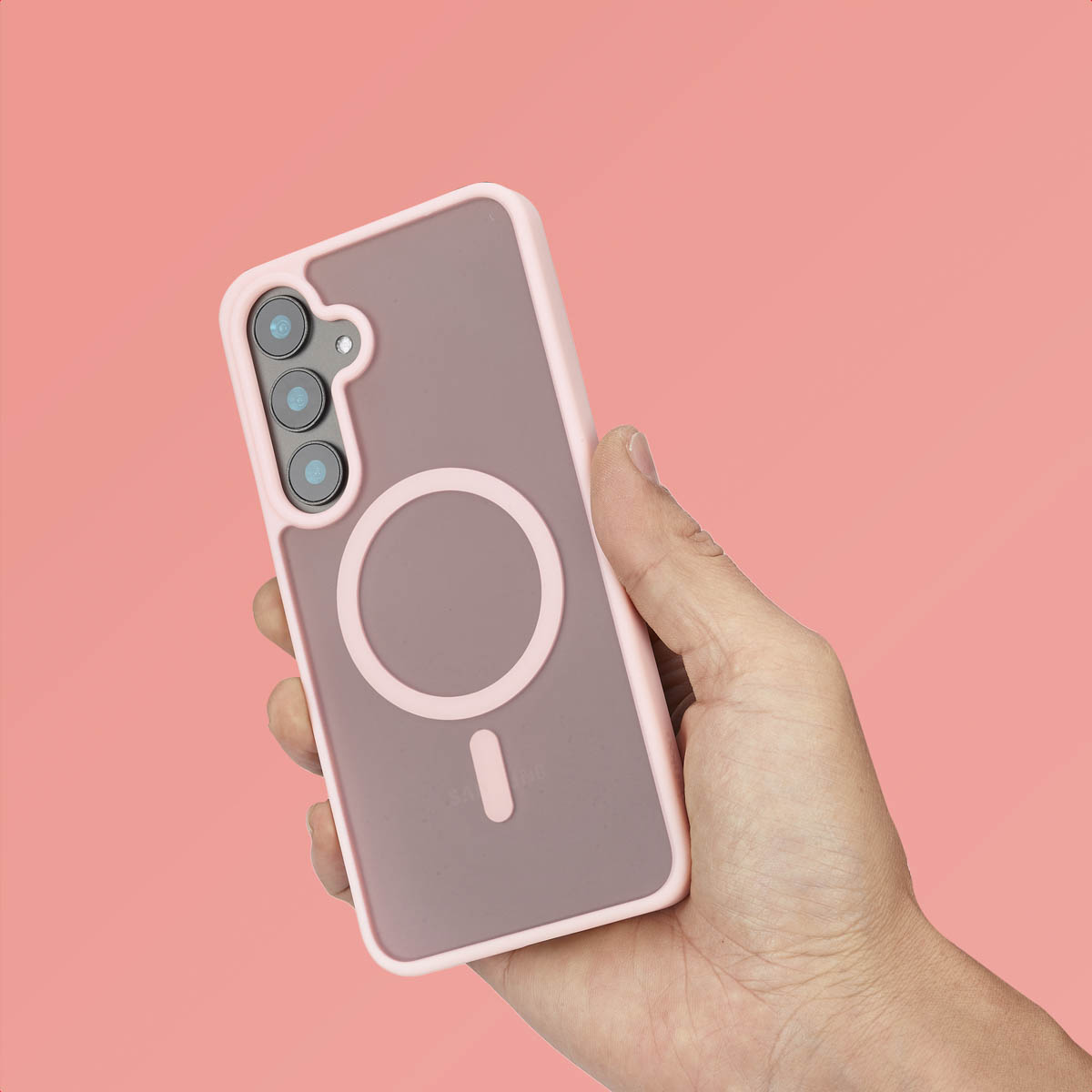 Een hand houdt een roze telefoonhoesje vast. De hoes heeft een MagSafe-ring. De tekst is niet zichtbaar.