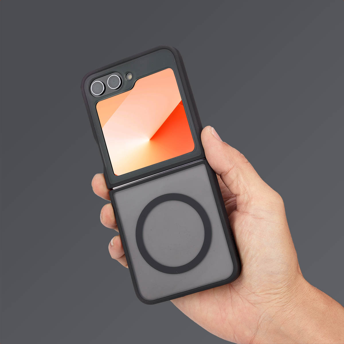 Hand die een zwarte telefoon in een hoes vasthoudt, de telefoon is open en toont een oranje scherm.