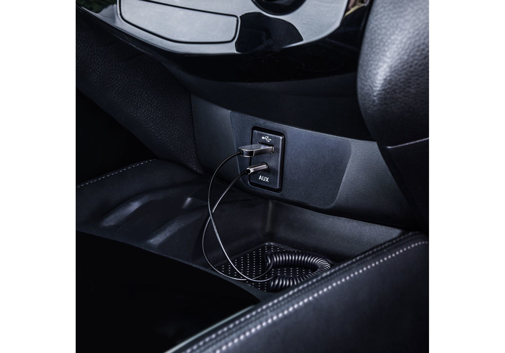 Porty USB i AUX w konsoli samochodu. Kable są obecne. Ciemne wnętrze.