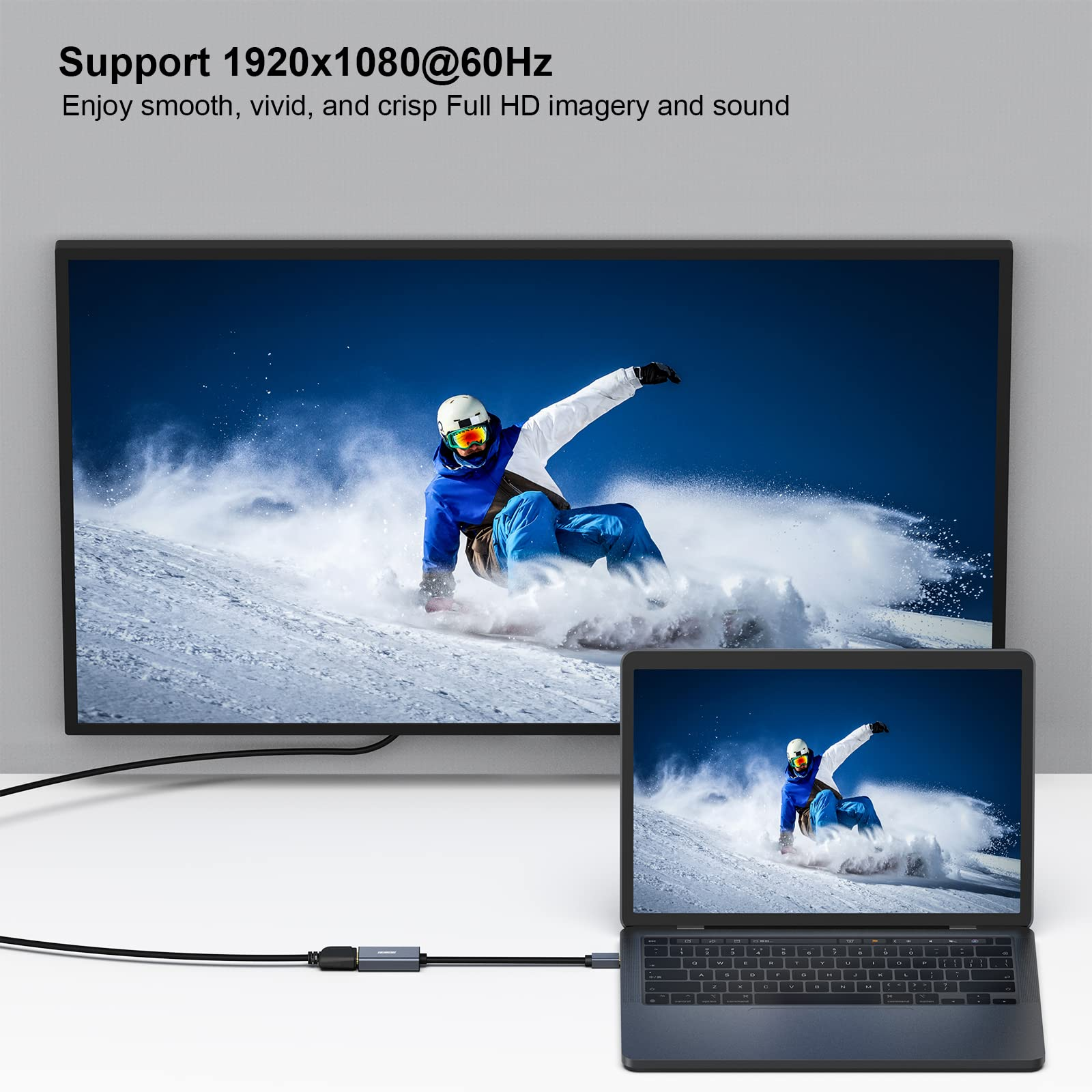 Ein Laptop und ein Fernseher zeigen einen Skifahrer auf einer verschneiten Piste. HDMI-Kabel verbindet sie.