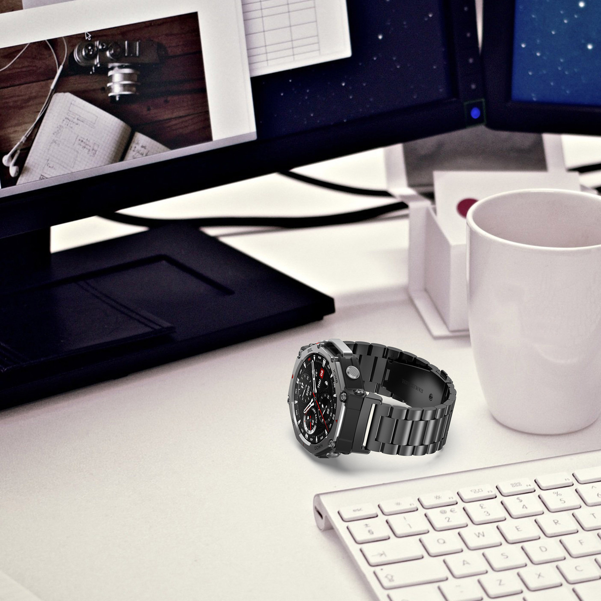 Schwarze Smartwatch auf einem Schreibtisch mit Tastatur, weißem Becher und Monitor.