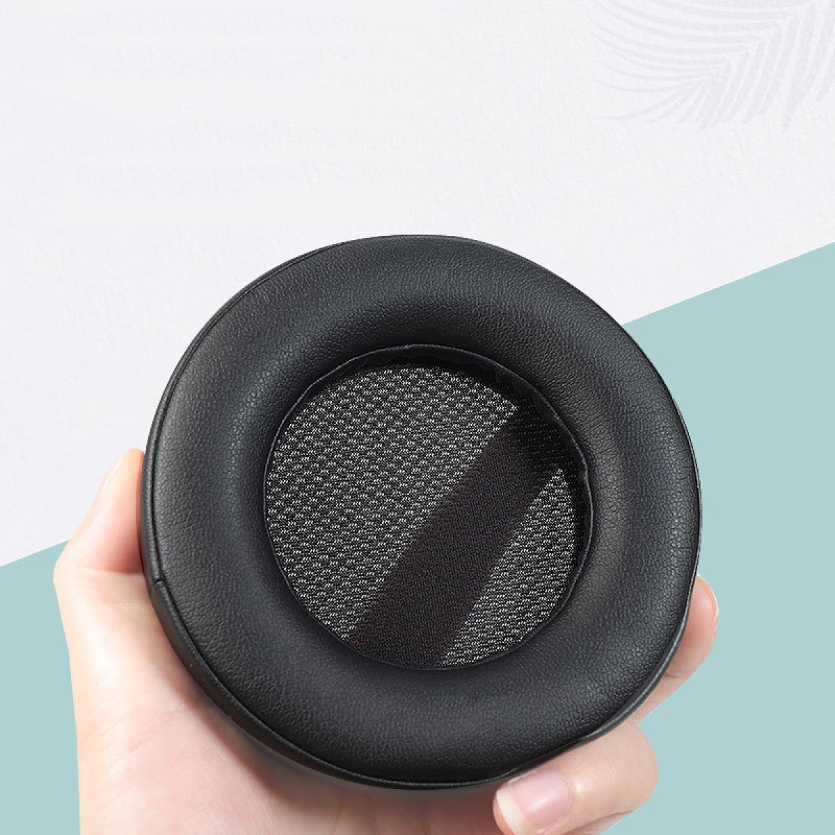 Czarna nauszniczka do słuchawek. Dłoń ją trzyma. Siatka w środku.