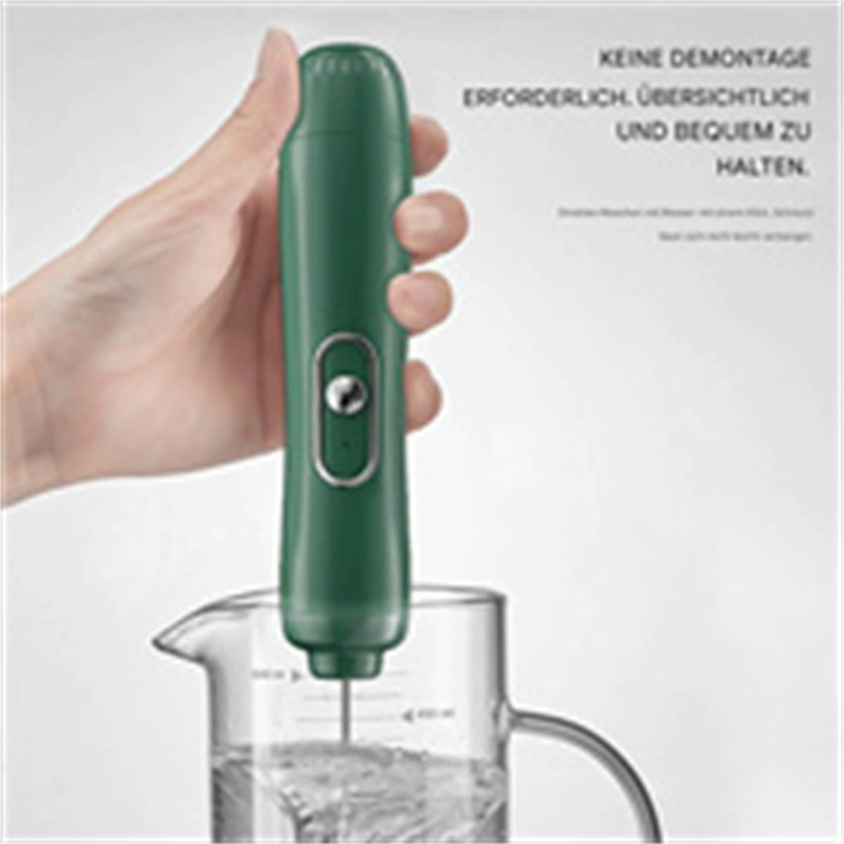 Eine Hand hält einen grünen Stabmixer. Er befindet sich in einem klaren Wasserglas, mit deutschem Text.