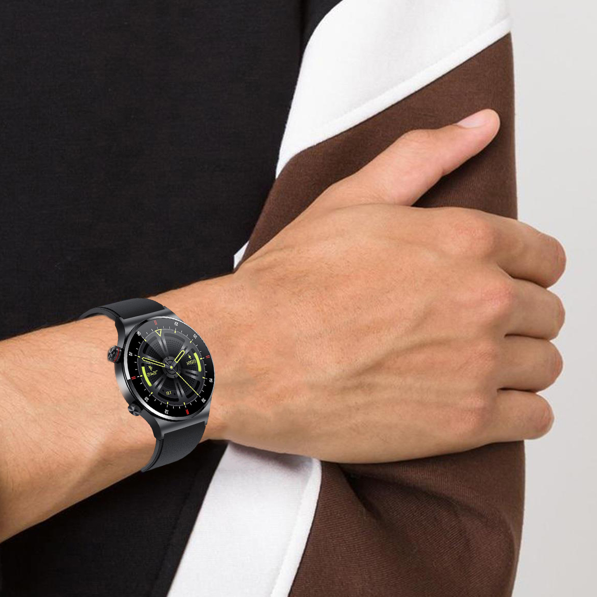 Mann trägt schwarze Uhr mit schwarzem Armband. Die Uhr hat ein schwarzes Zifferblatt. Mann trägt braunes und weißes Oberteil.
