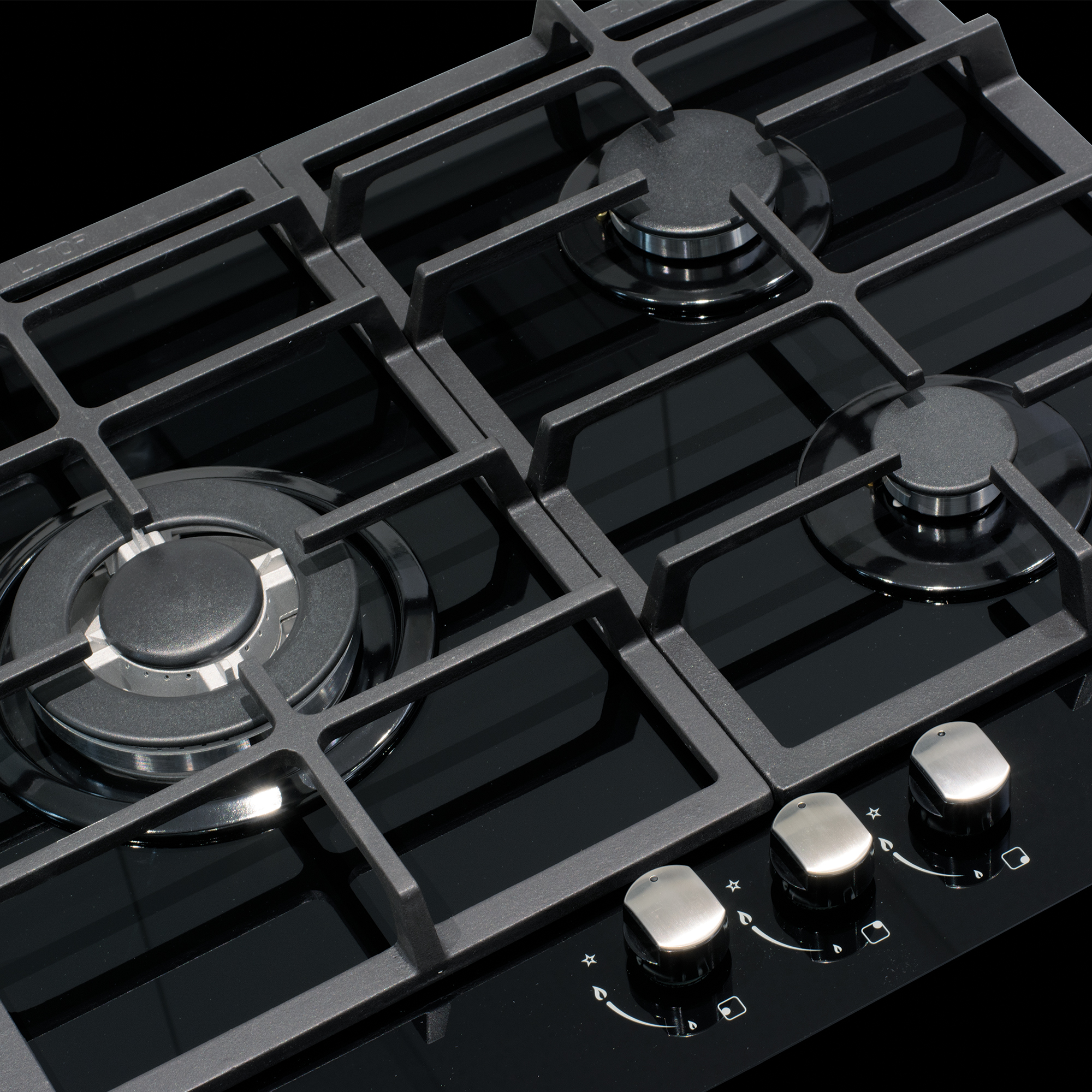 Zbliżenie czarnej kuchenki gazowej z palnikami i pokrętłami. Czarna powierzchnia.