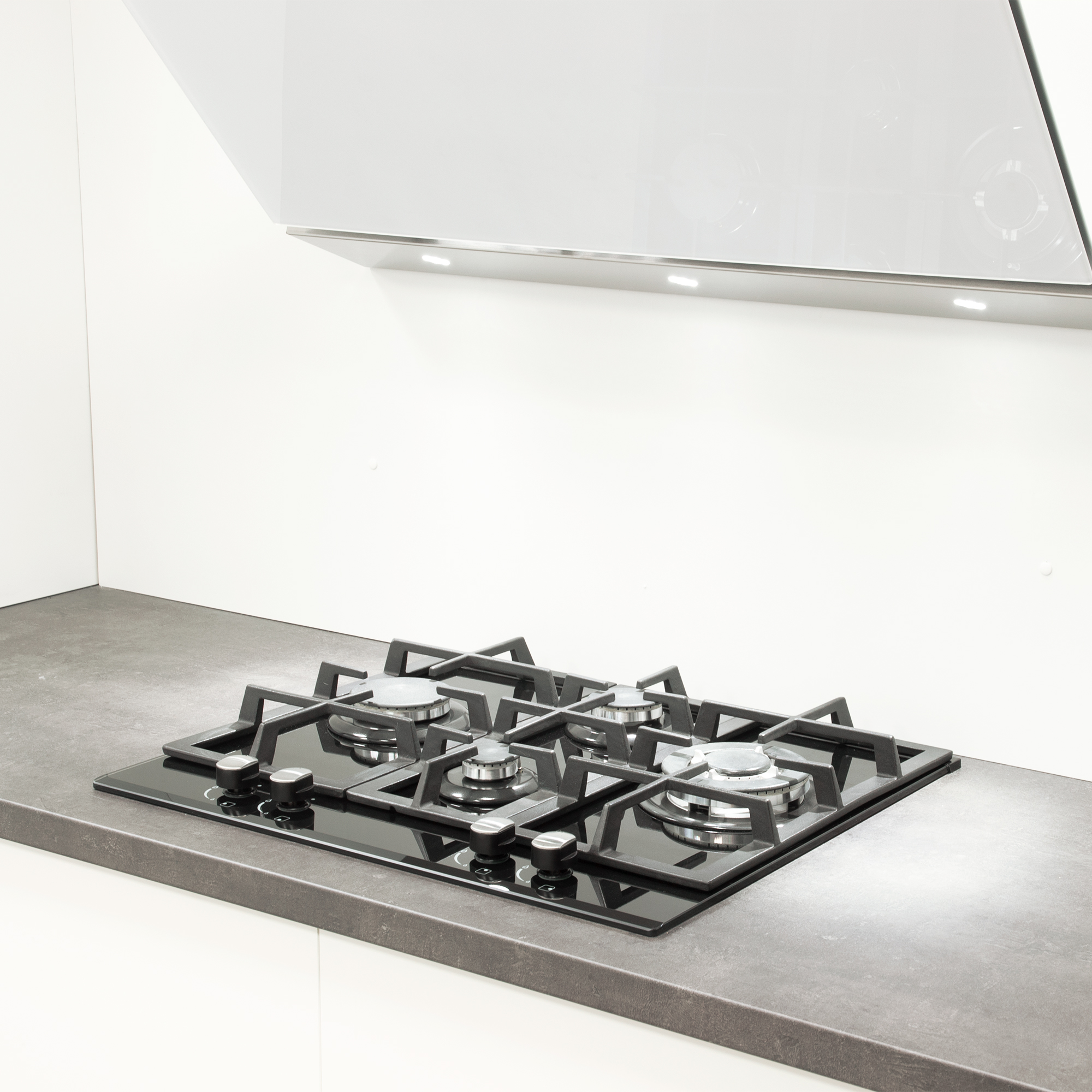 Czarna płyta grzewcza ze szkła z czterema palnikami. Białe tło.