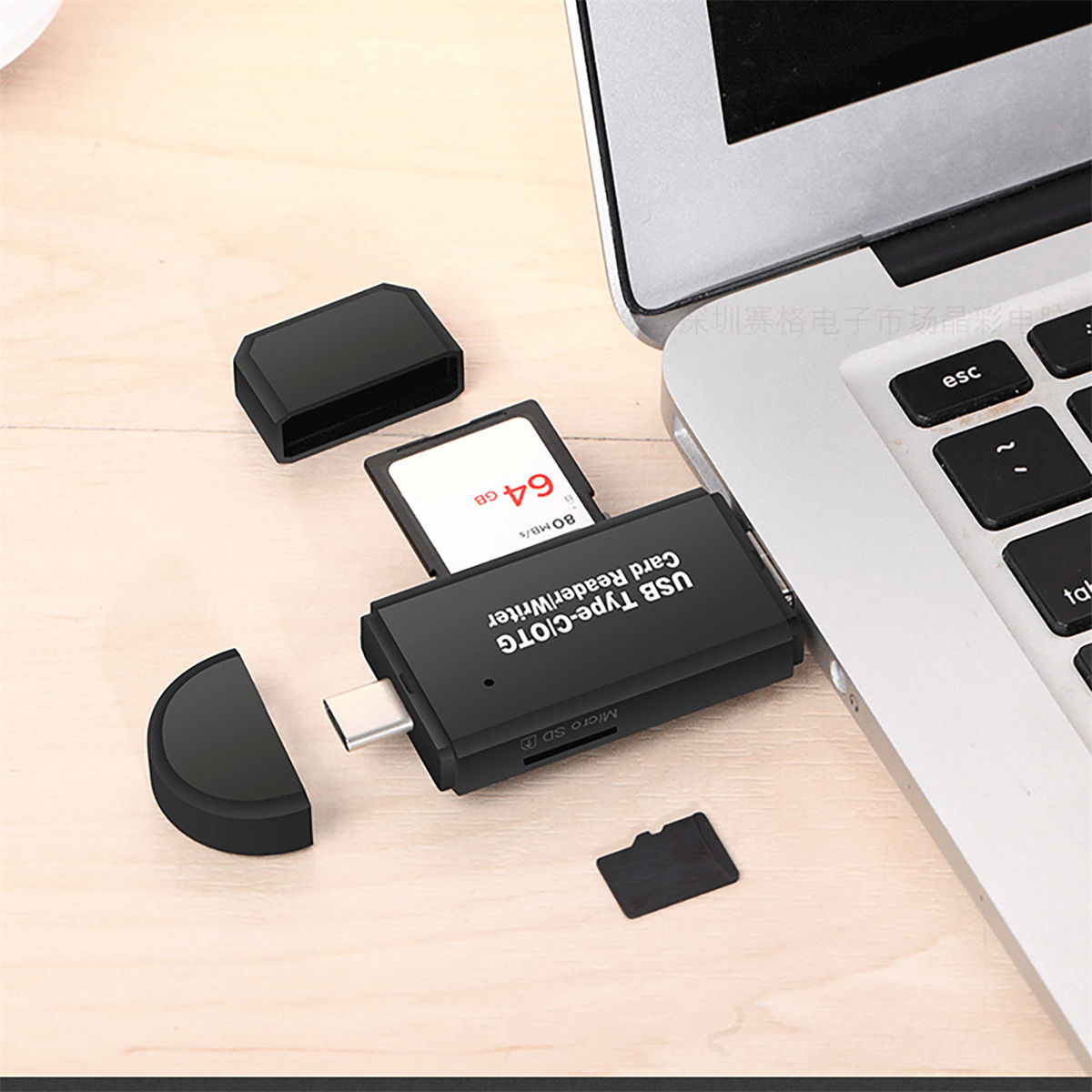 Ein Kartenleser mit einer 64GB SD-Karte und zwei schwarzen Abdeckungen. Ein Laptop im Hintergrund.
