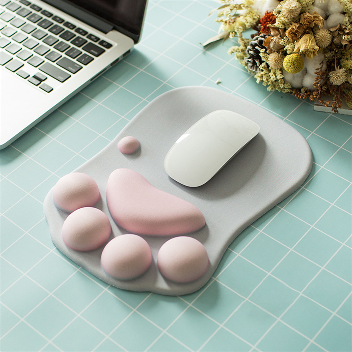 Mauspad in Form einer Katzenpfote. Rosa Pads und eine weiße Maus auf blauer Gitteroberfläche.