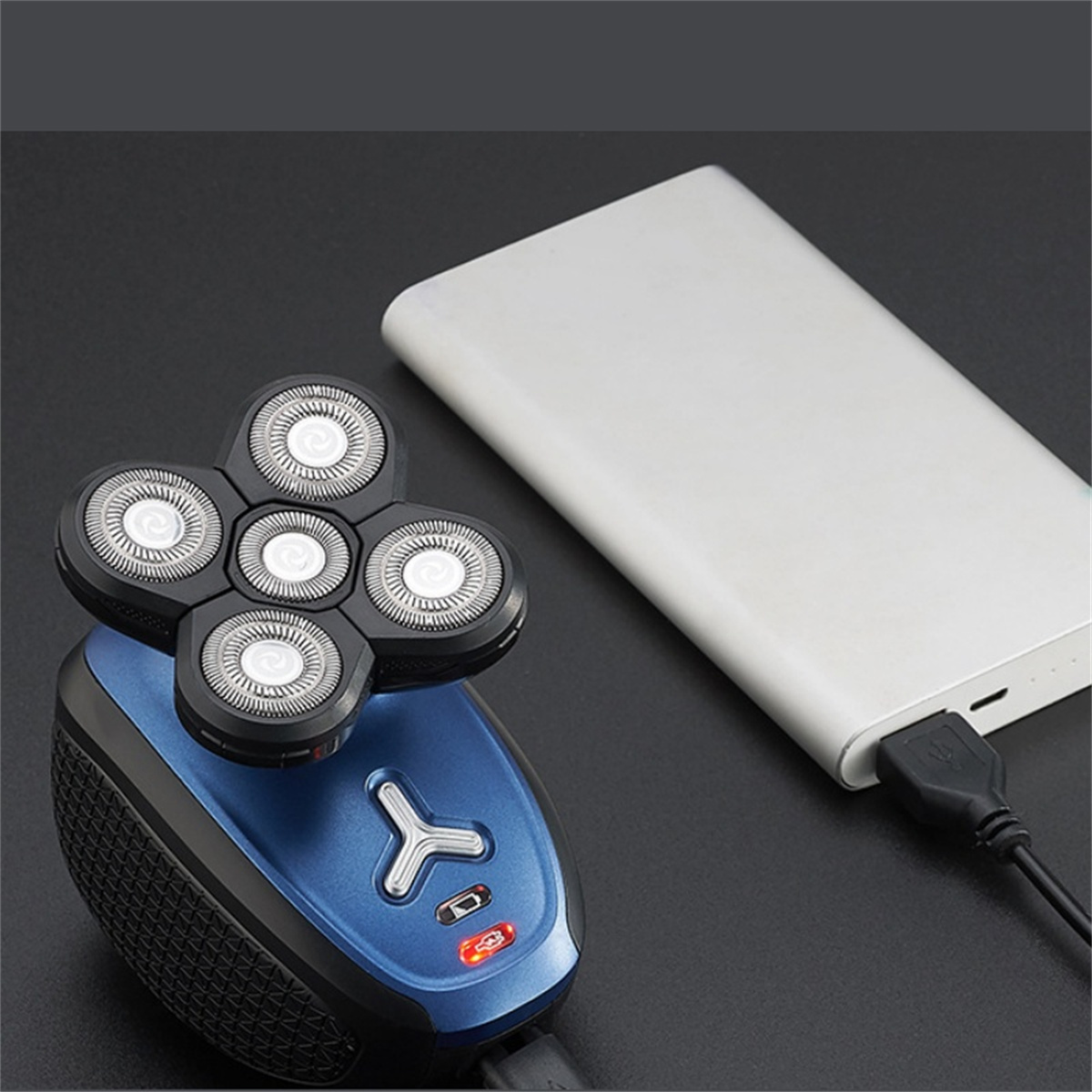 Blauer und schwarzer Elektrorasierer mit einer Powerbank auf schwarzem Untergrund.