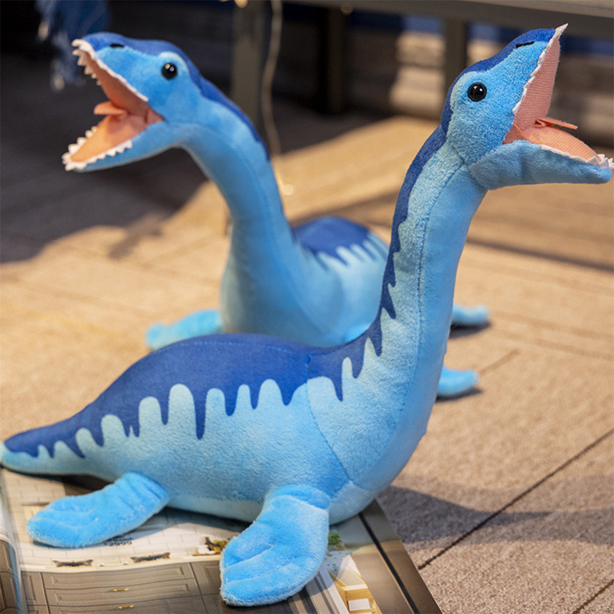 Zwei blaue Plesiosaurier-Plüschtiere mit geöffneten Mäulern.