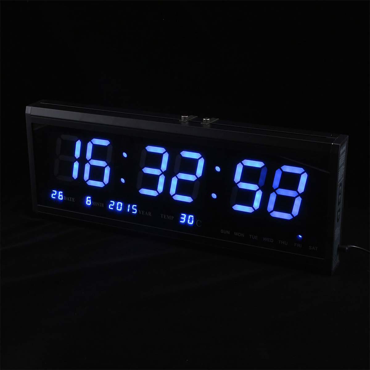 Eine Digitaluhr, die die Uhrzeit, das Datum und den Wochentag anzeigt. Die Anzeige ist blau. Schwarzer Hintergrund.